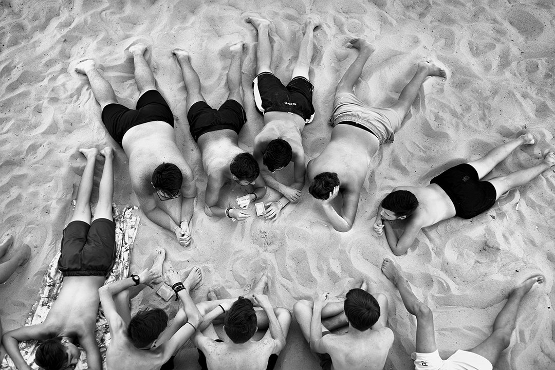 A group lying in a circle on the sand, seen from above.